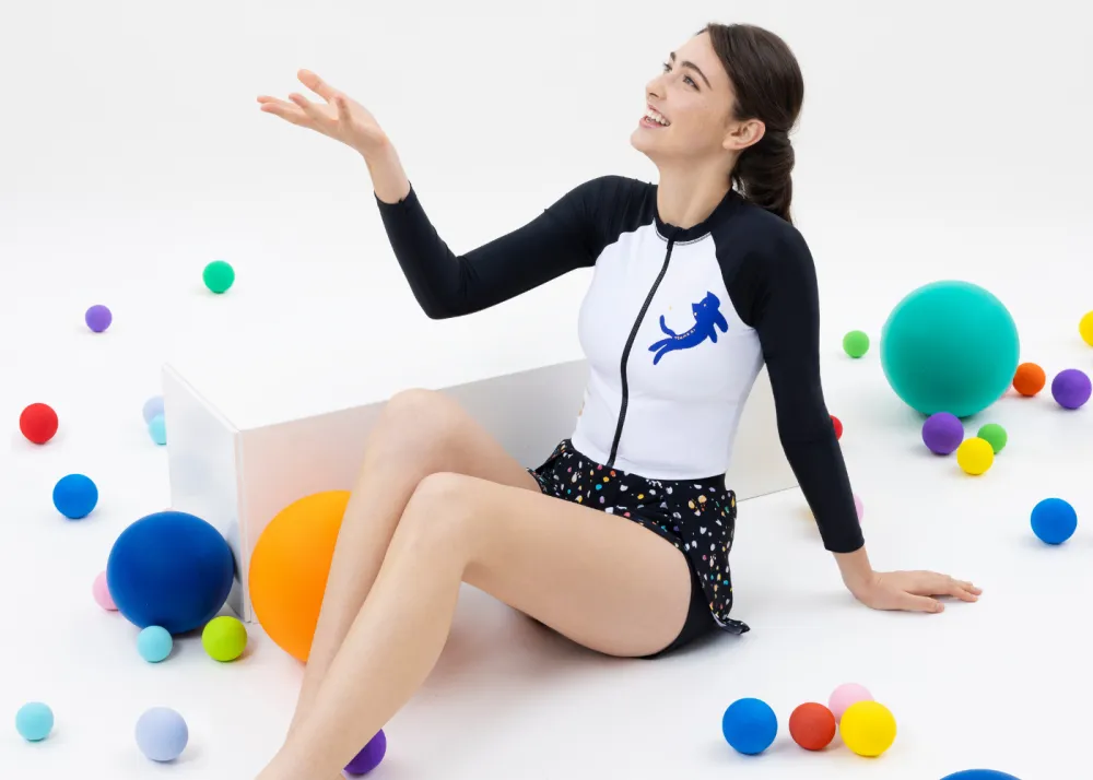 Lifestyle photo of a model wearing the Ladies Cat Graphic Long Sleeves Crop Sun Protection Top and Dot Print 2 in 1 water shorts