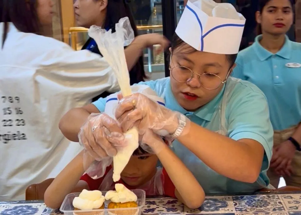 StarCruises’ “Star Voyager” crew member teaching child guest cooking