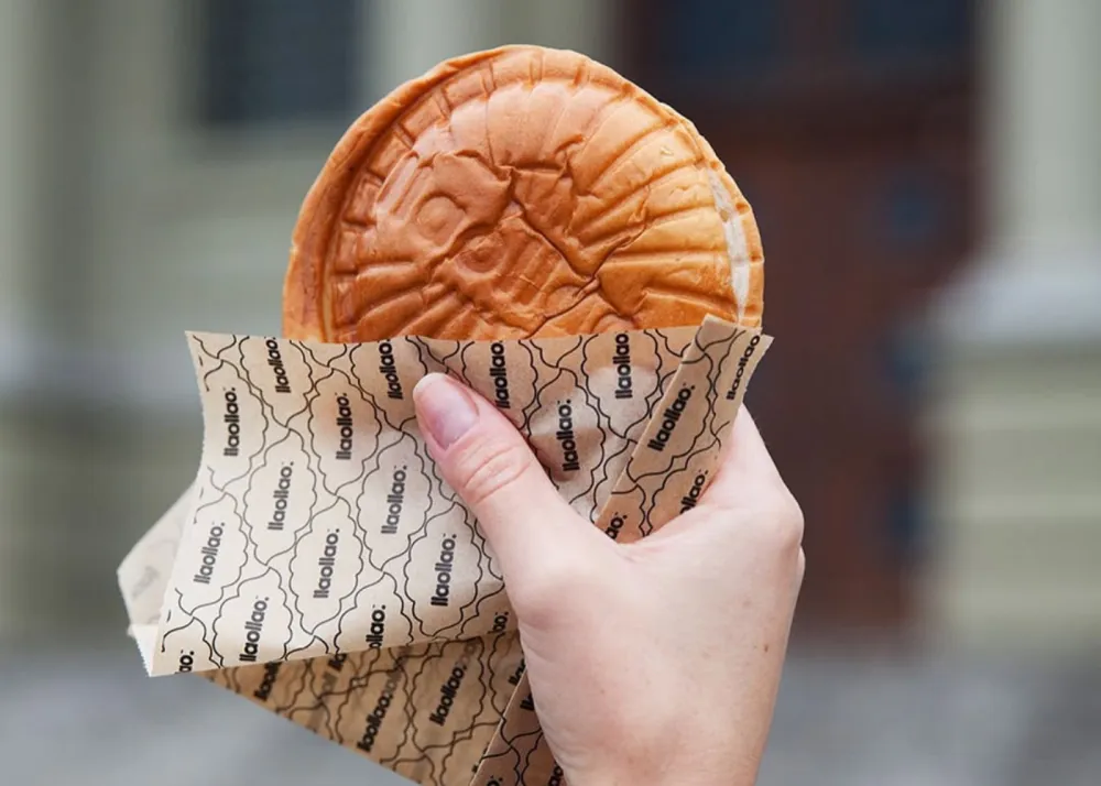 A hand holding a brioche bun