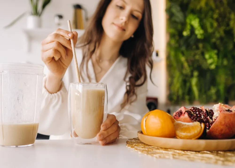 A woman mixing a drink with fruits in the background