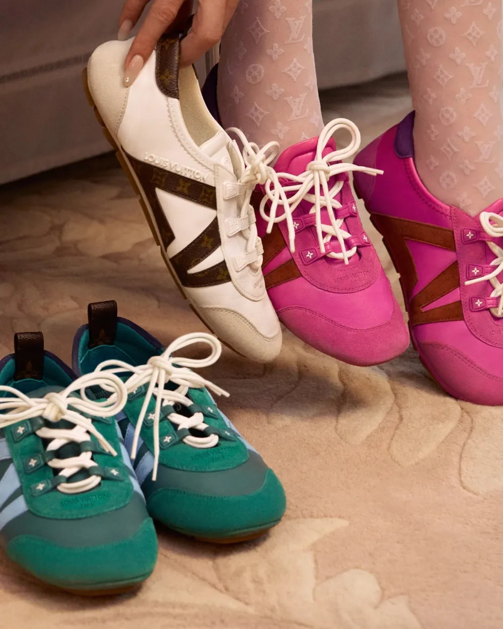 A woman displays three pairs of LV Sneakerinas, showcasing different styles and colors in her hands.