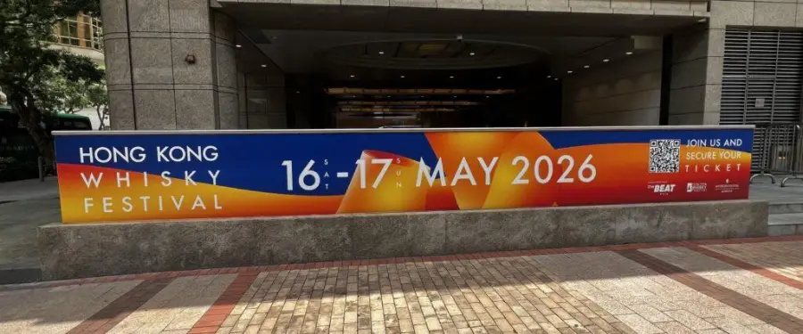 A banner outside a building announces the “Hong Kong Whisky Festival, 16-17 May 2026.” The colorful sign encourages people to join and secure tickets, with event details prominently displayed.