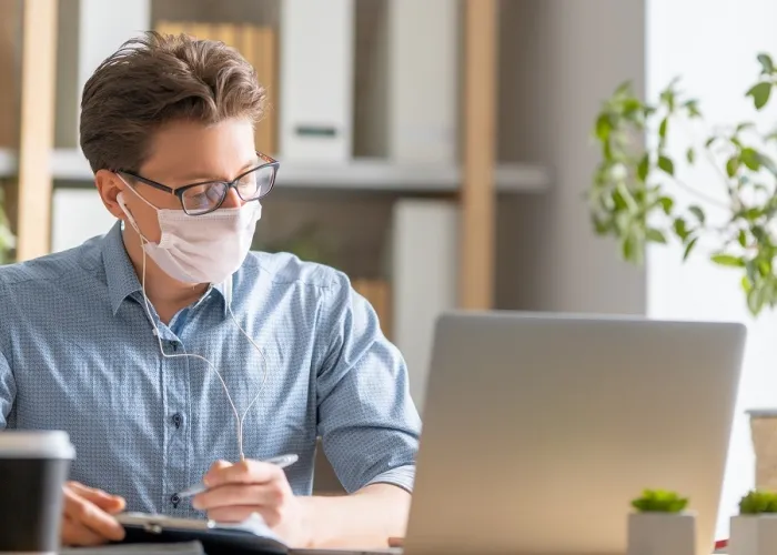 Man in face mask is working on a laptop 2021 08 30 19 04 40 utc