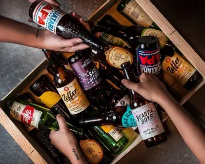 Hands holding beers from a crate
