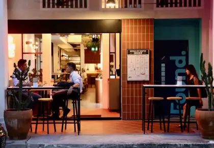 Exterior shot of a restaurant or bar with high tables and people sitting outside