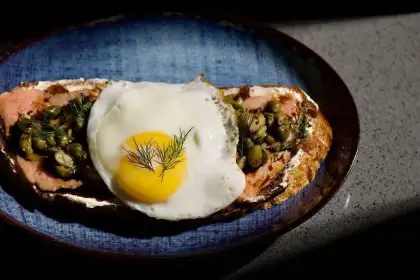 Salmon toast dish topped with sunny egg with fennel cheese.