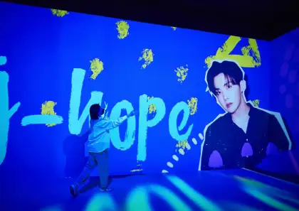 Fan taking a picture at the J-Hope wall at the D'Festa Exhibition