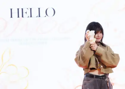 Artist Ayan Deng taking a photo with a DIMOO figurine