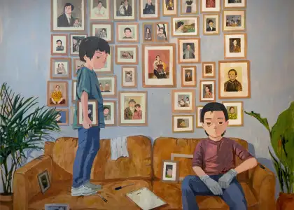 Two boys with a sofa and a row of frames behind them