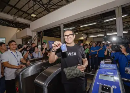 A person holding a card in between turnstiles, surrounded by press
