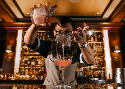 A bartender pouring a drink into a glass