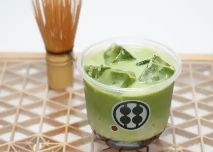 A matcha drink with a matcha whisk