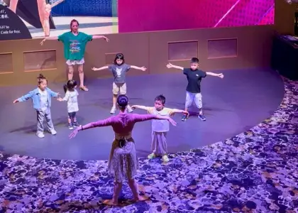 StarCruises’ “Star Voyager” lobby with crew member teaching ballet to child guests