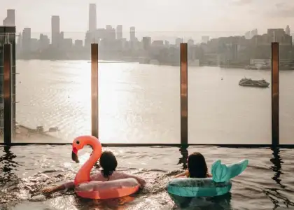 Two women enjoying the infinity pool views of Hong Kong's skylines on colourful floaties at Hyatt Centric Victoria Harbour Hong Kong hotel