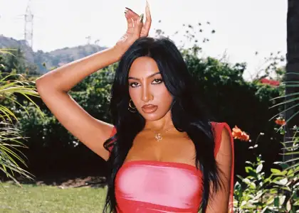 KATSEYE member Lara Rajagopalan in pink dress and green background