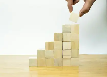 A person placing a piece of wood into a pyramid