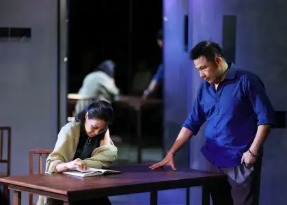 A woman reading while a man stands over her