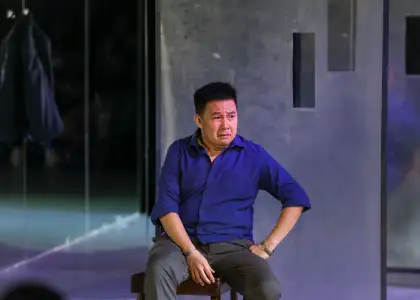 A man in a blue polo shirt sitting with a despaired look on his face