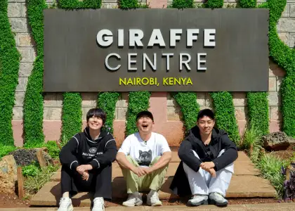 A group of three people in front of a sign