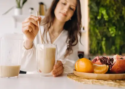 A woman mixing a drink with fruits in the background