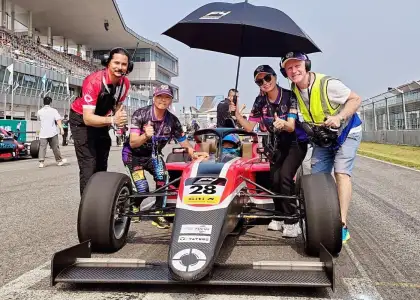 Hong Kong racecar driver Vivian Siu and star of documentary Zero to Macau posing in racecar with award winning documentarian Jonathan Finnigan and film crew