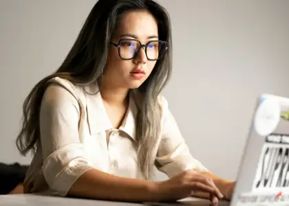 A woman wearing glasses typing on her laptop
