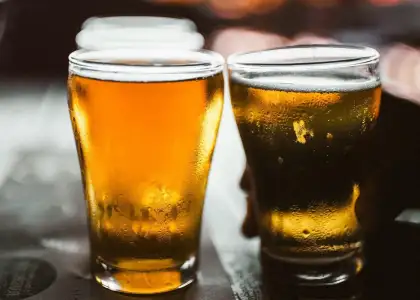 A close-up photograph captures two chilled glasses of beer, with condensation droplets clinging to the sides, hinting at refreshment.