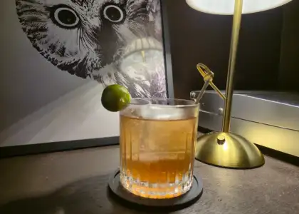 A light colored cocktail with a calamansi as garnish