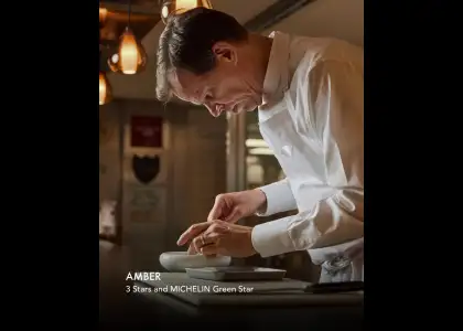 A man in a white shirt is chopping vegetables while preparing food in a kitchen setting.