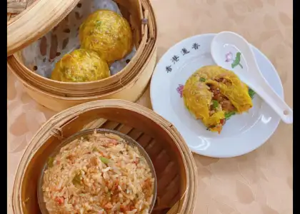 Two plates of food served in bamboo baskets on a wooden table, showcasing a colorful and appetizing meal.