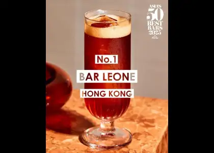 A glass filled with red liquid and a straw, placed on a wooden table.