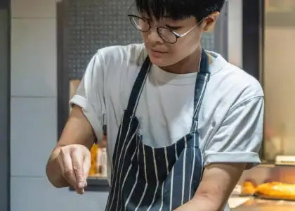 A young man in an apron skillfully preparing food in a modern kitchen.