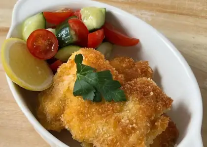 A plate of cooked fish accompanied by colorful vegetables, elegantly arranged on a dining table.