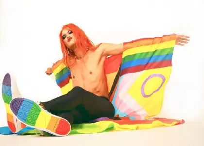 Drag Race Thailand Season 1 contestant drag queen Amadiva posed seated shirtless with pride flag