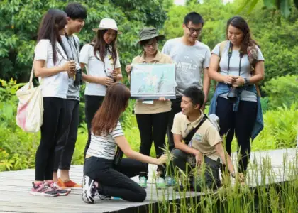 People enjoying and exploring Hong Kong Wetland park with guide posed on boardwalk surrounded by nature