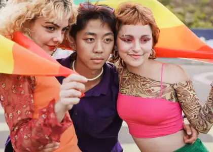 Young diverse friends having fun with LGBT rainbow flag at pride parade