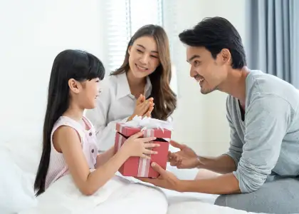 Asian lovely young little daughter open present gift box from parents
