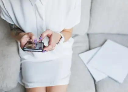 Phone in hands of girl in white dress sitting on g KRJ5 CQ7