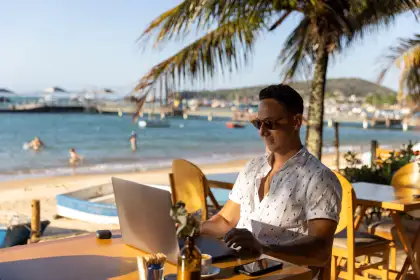 Man using laptop at a beach cafe