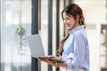 Asian woman using laptop near window