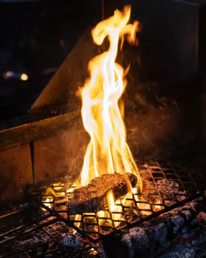 Steak being grilled over an open flame.