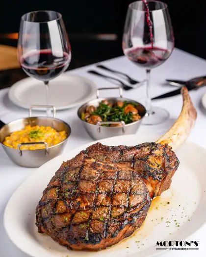 A large steak with sides and red wine