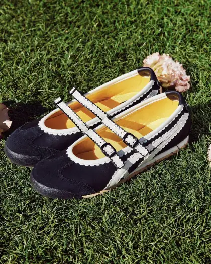 A pair of black and white Onitsuka Tiger Ballerina shoes resting on green grass.