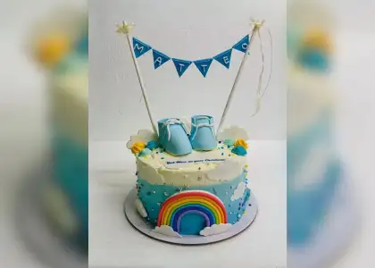 Blue and white cake with booties and rainbow decor