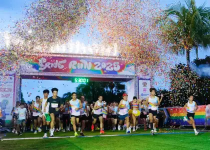 Runners burst from the starting line at the Pride Run 2023 under a colorful arch amid a shower of confetti