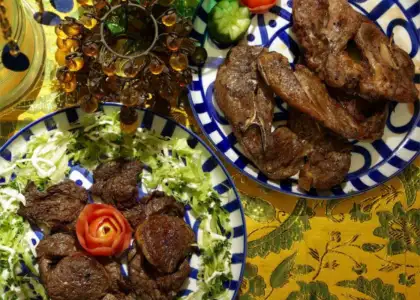 Two blue-patterned plates filled with grilled meat sit on a vibrant yellow tablecloth