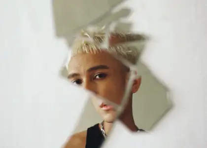 Firdhaus is reflected in shattered mirror fragments against a pale background, creating a fragmented and introspective mood