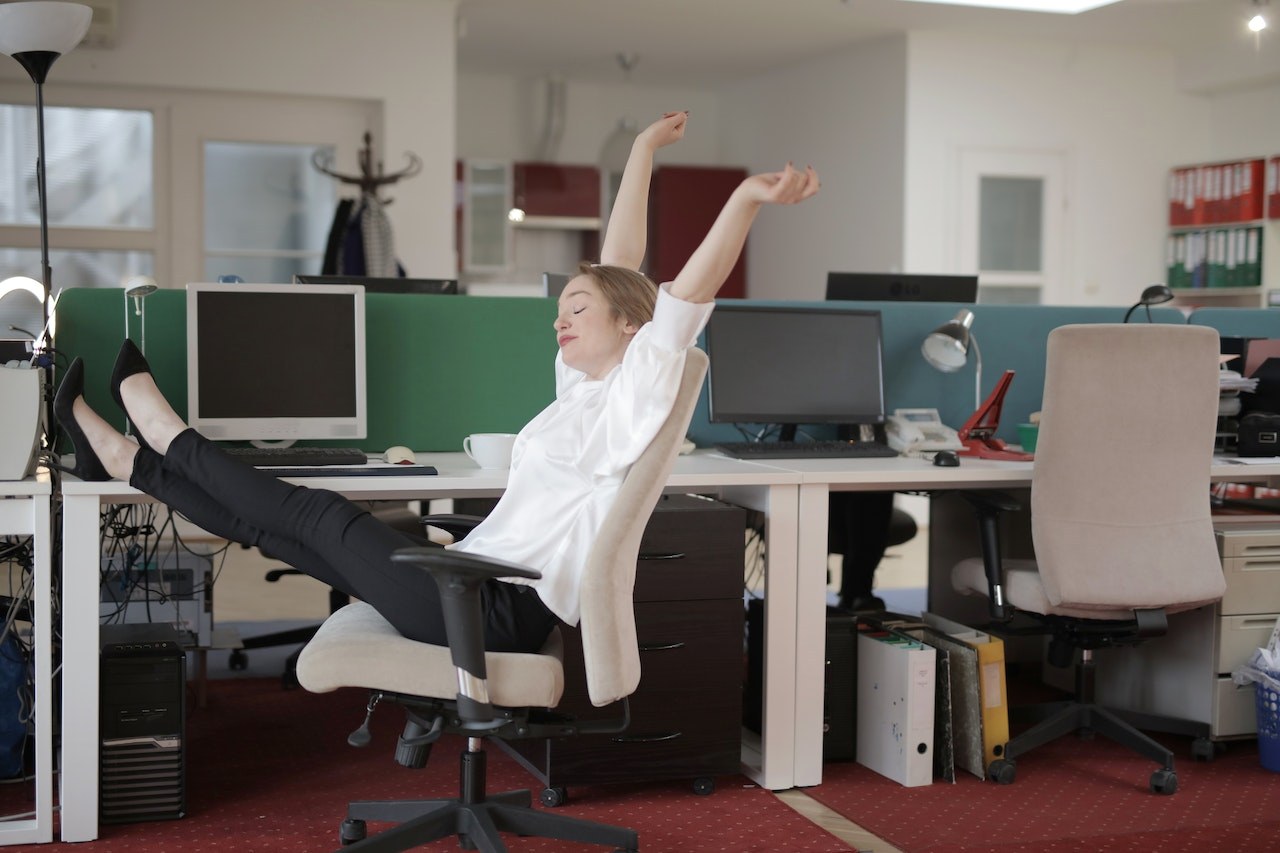 woman at work stretching arms and raising feet