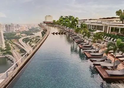 Marina Bay Sands hotel and casino, featuring its iconic three towers and rooftop infinity pool against a clear blue sky.